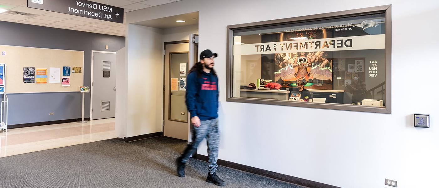 A student strolls past the outside of the main office of MSU Denver Art.