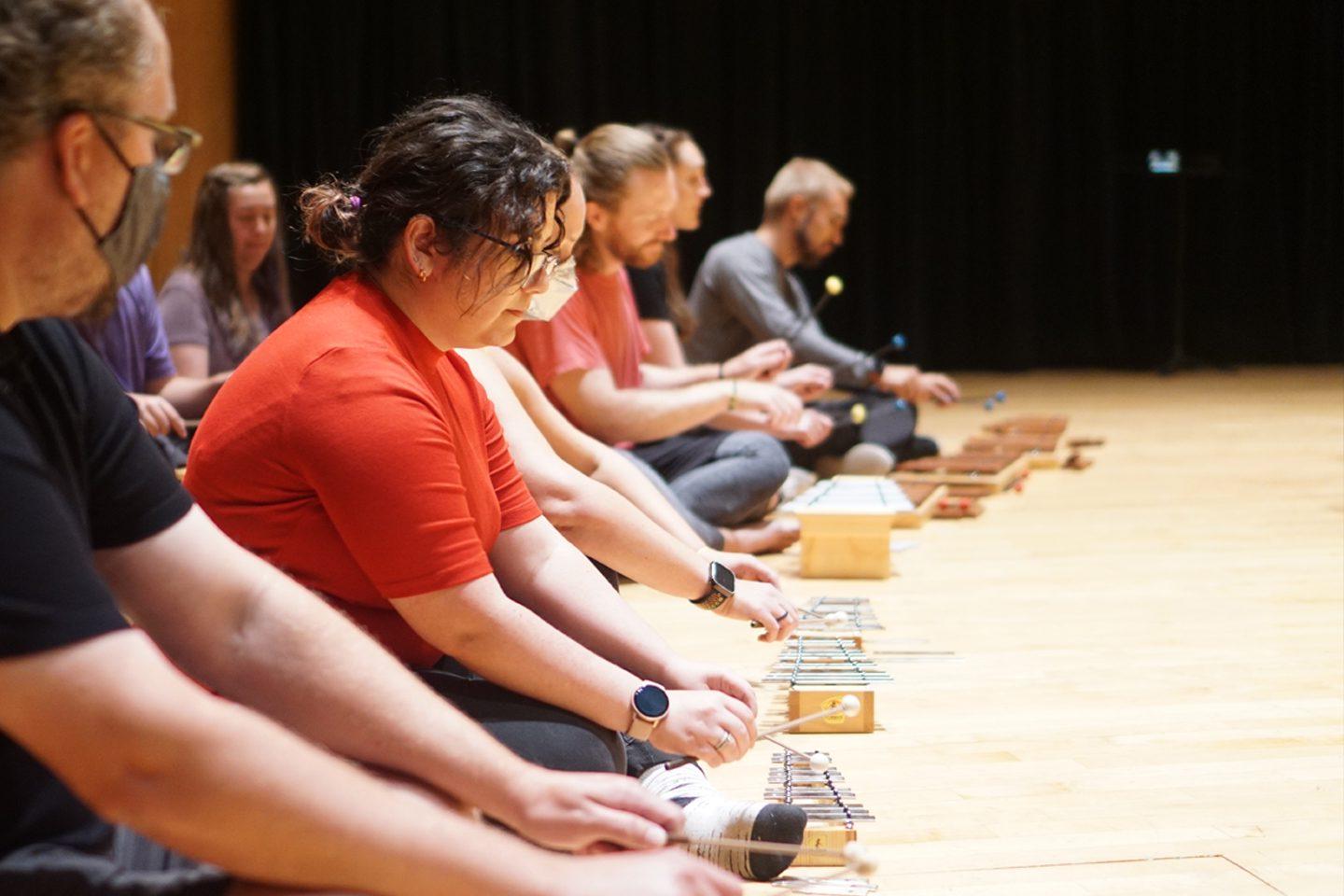 Musicians sitting on a stage playing small xylophones